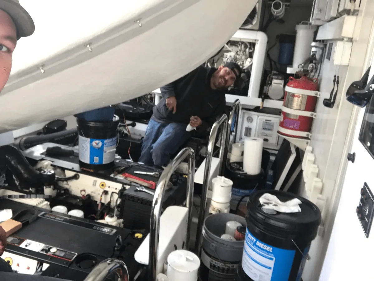 Marine mechanic working on a diesel engine inside a boat engine bay